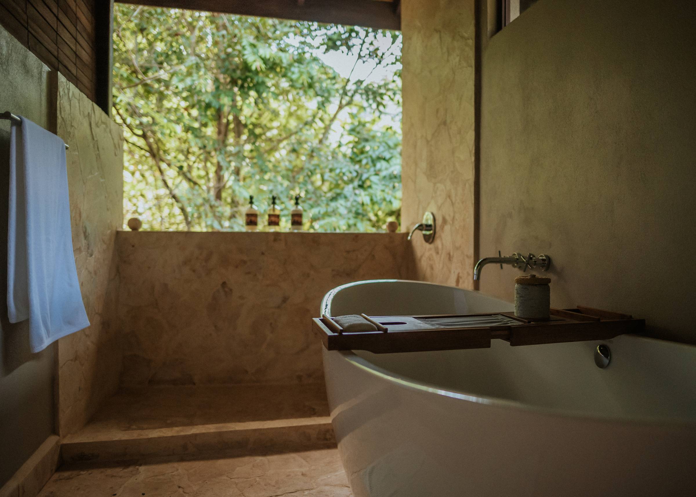 A deep soaking tub and outdoor shower open air to the Costa Rican rainforest at Imiloa, the ecoresort hosting a luxury HSP retreat.
