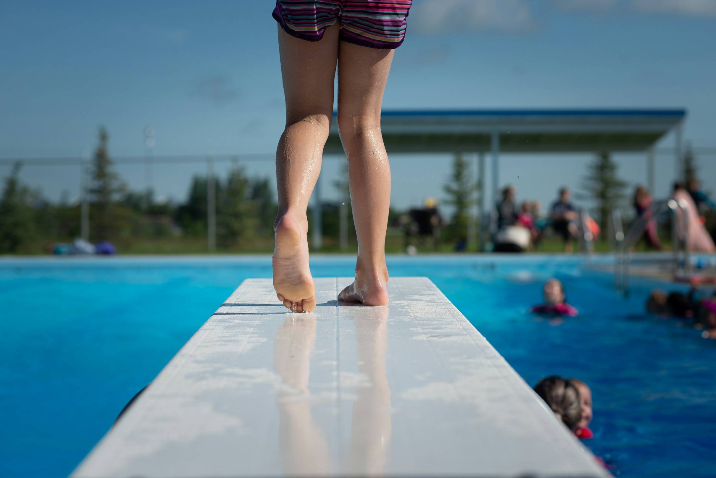 child on high diving board at public pool