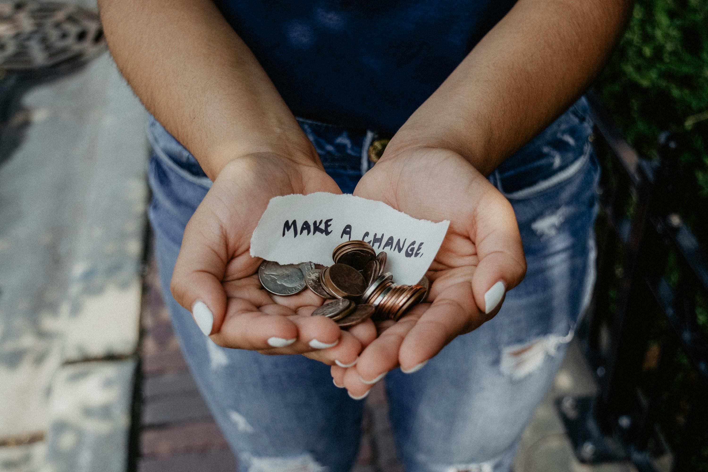 An image of a person holding a handful of coins out to you, along with a note that says "Make a Change".