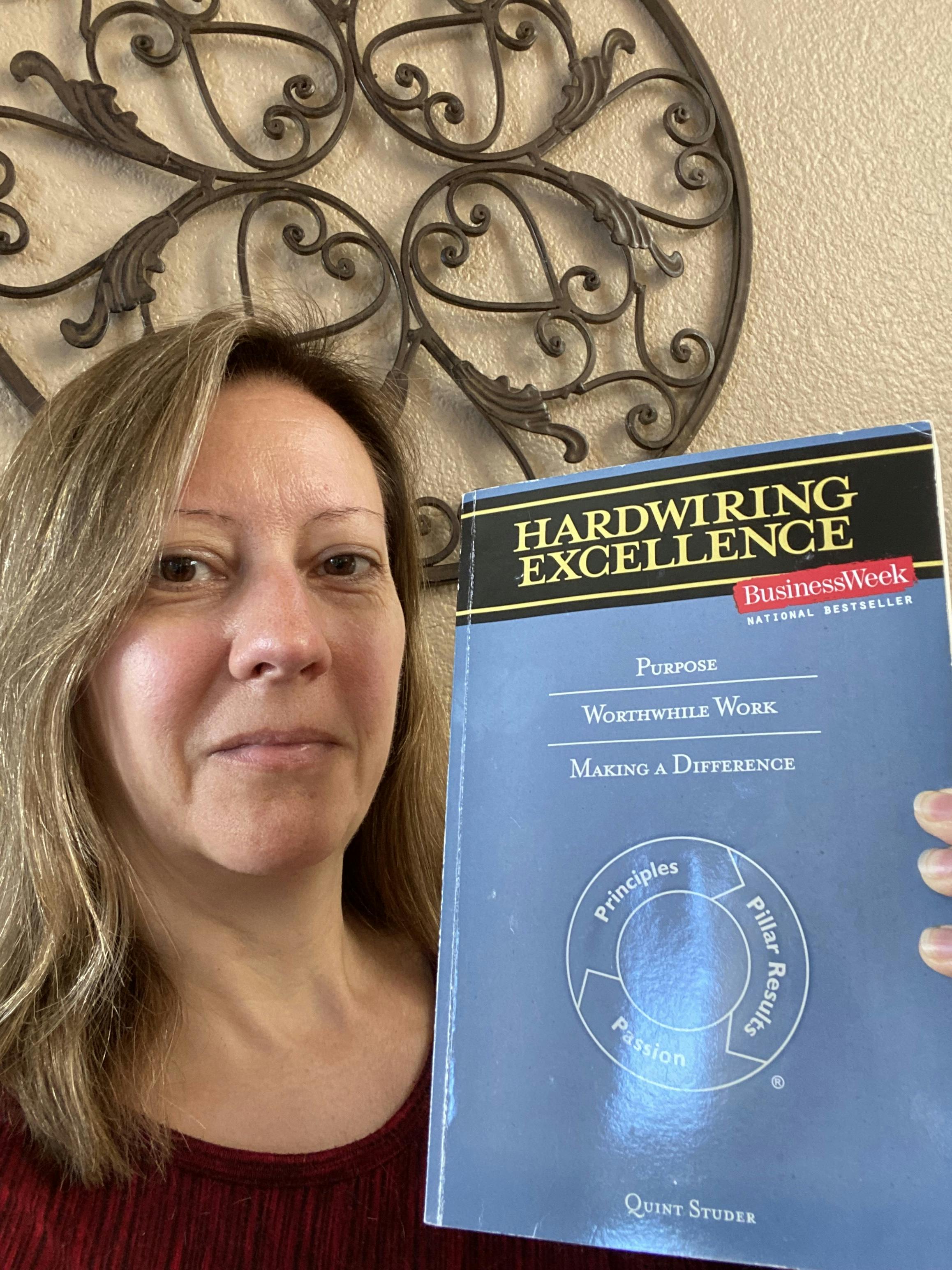 Stephanie holding up the book "Hardwiring Excellence" by Quint Studer.