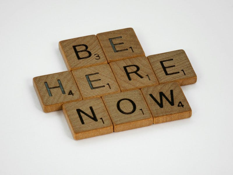 Scrabble tiles spelling out the words: "Be Here Now"
