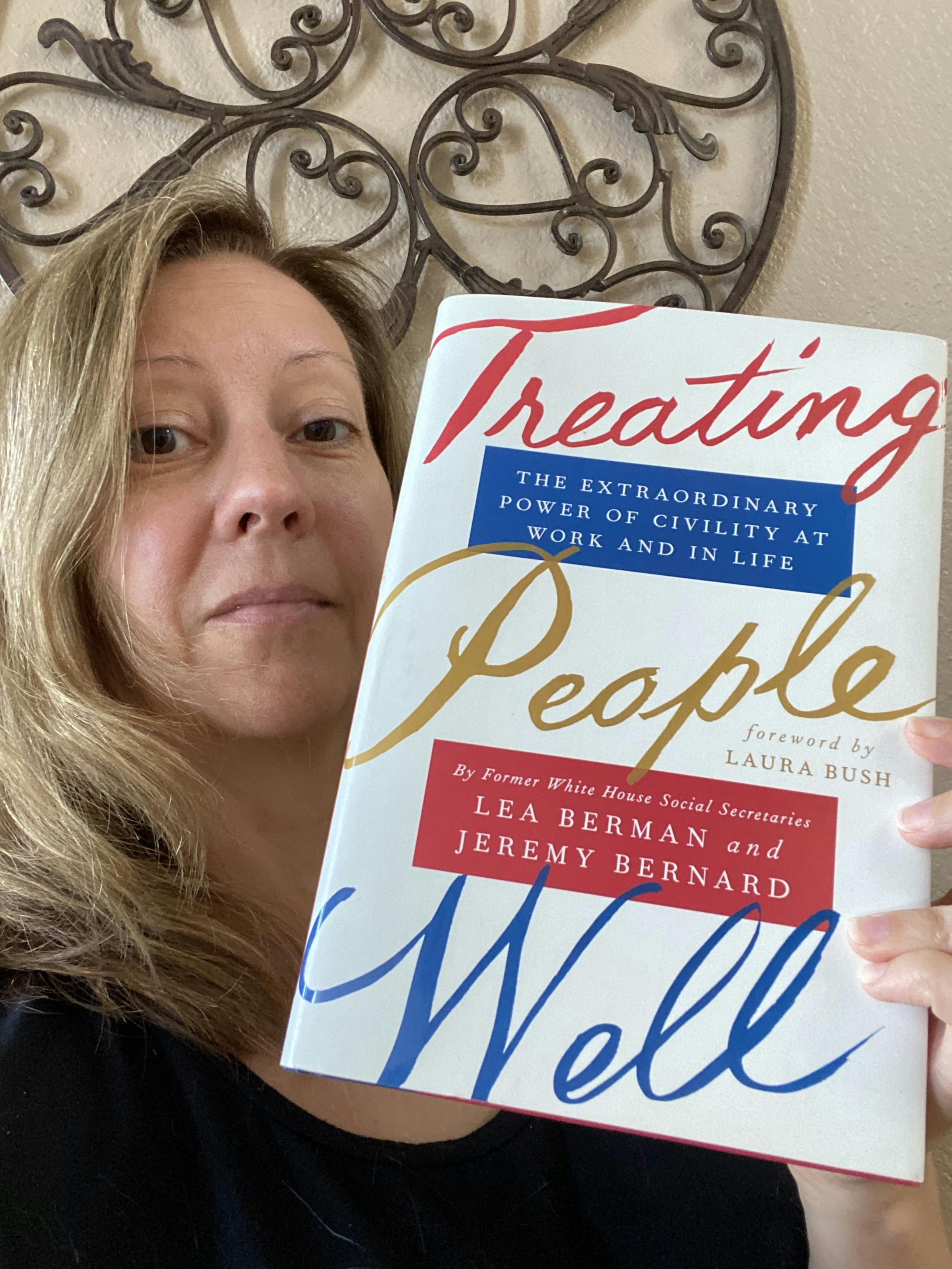 Stephanie holding the book "Treating People Well: The Extraordinary Power of Civility at Work and in Life" by Lea Berman & Jeremy Bernard.