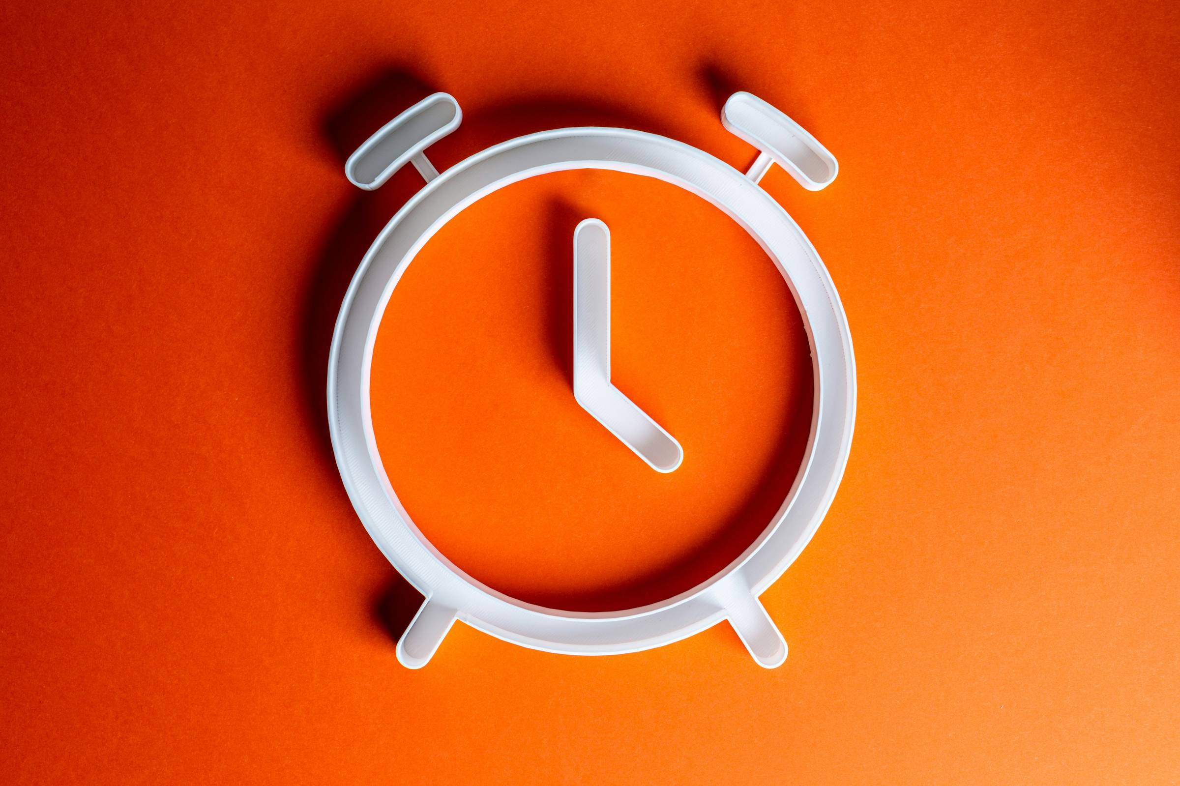 An orange background highlights a white outline of an alarm clock