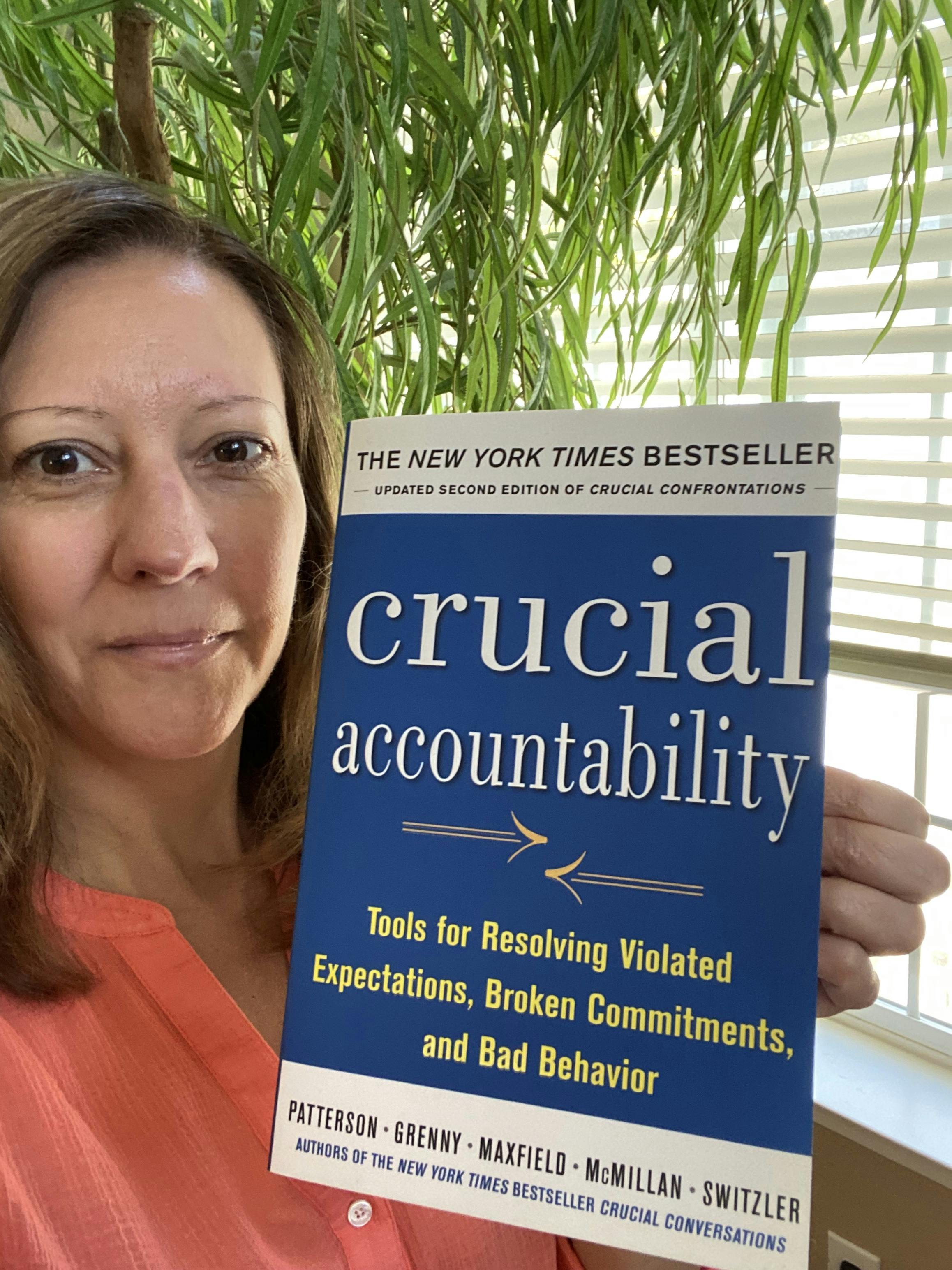Stephanie holding up the book "Crucial Accountability"