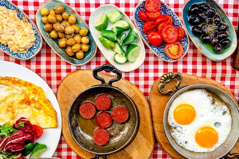 A spread of turkish breakfast dishes with olives and eggs.