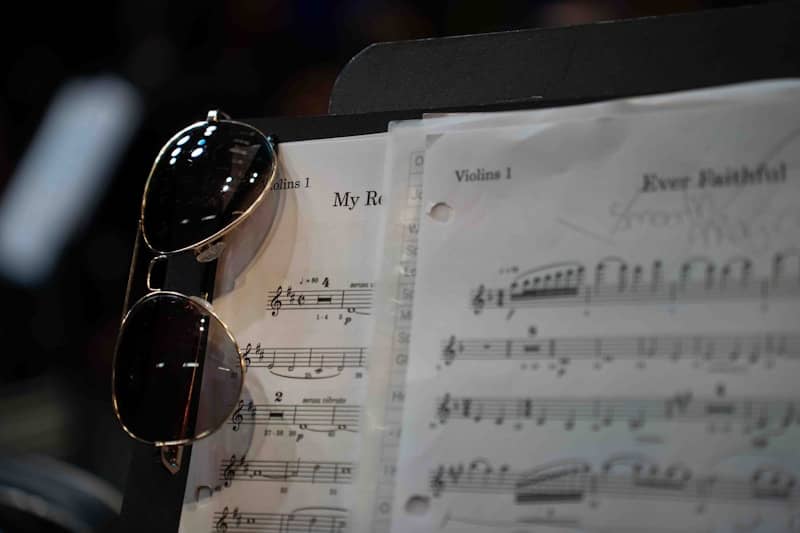 Sunglasses resting on a music stand with sheet music.