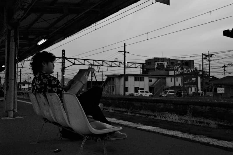 Person reads on a bench at a train station.
