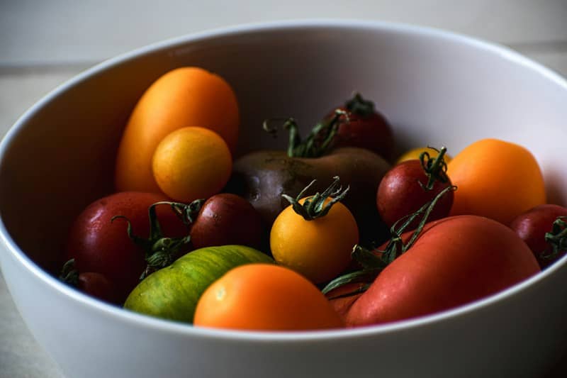 A variety of colorful heirloom tomatoes in a white ceramic bowl
