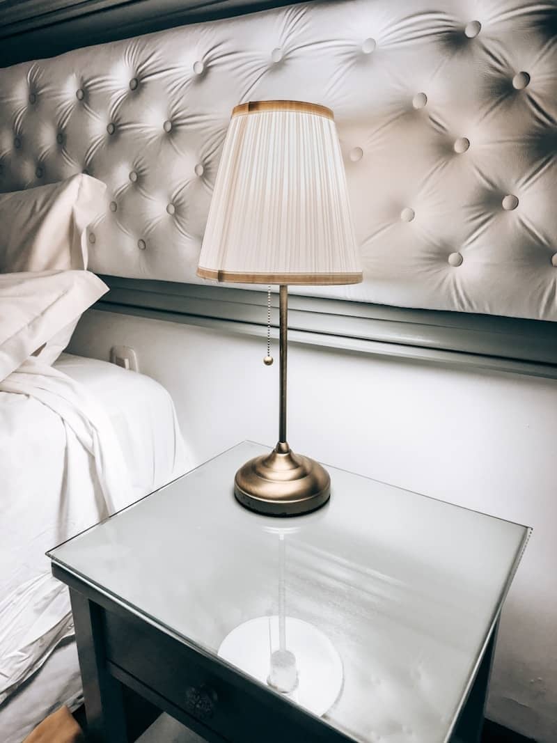 A bedside lamp sits on a glass-top nightstand.