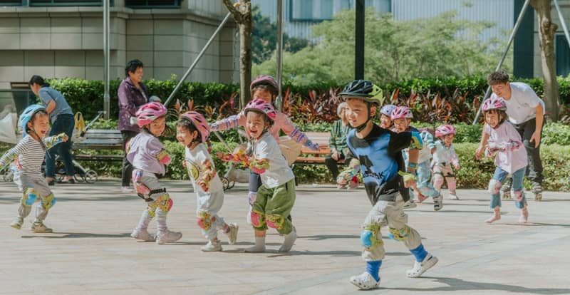 Children wearing helmets play outside on a sunny day.