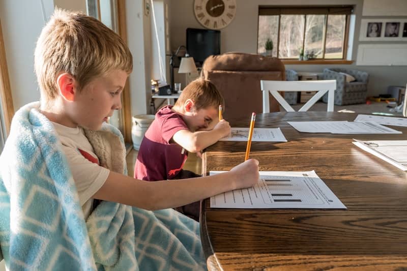 boy in gray crew neck t-shirt doing homework