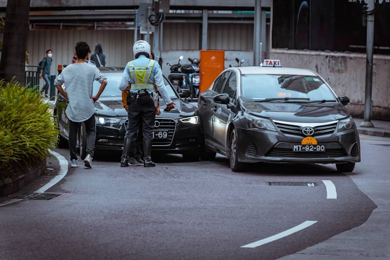 Two people look back at a car accident on the road.