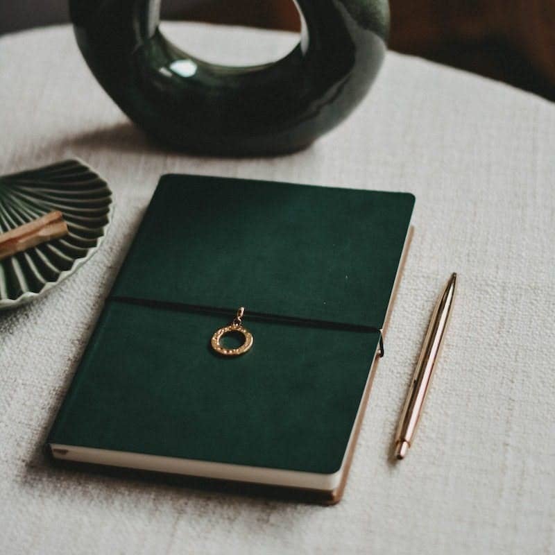 black and silver round ring on green book