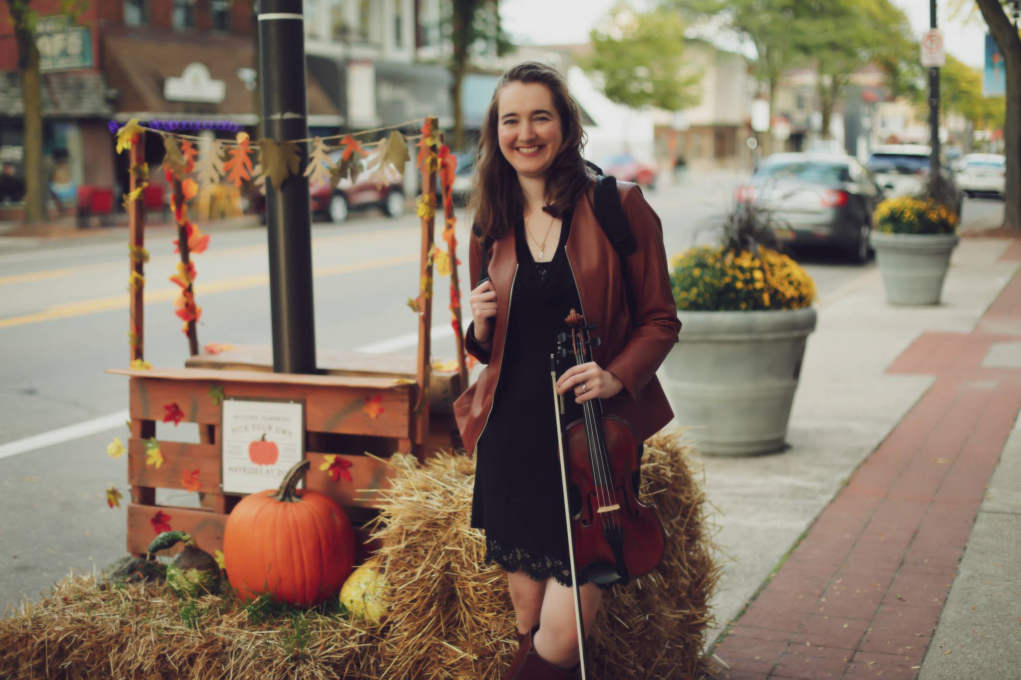 Hannah stands next to a pumpkin and haybale display in a small town in Michigan