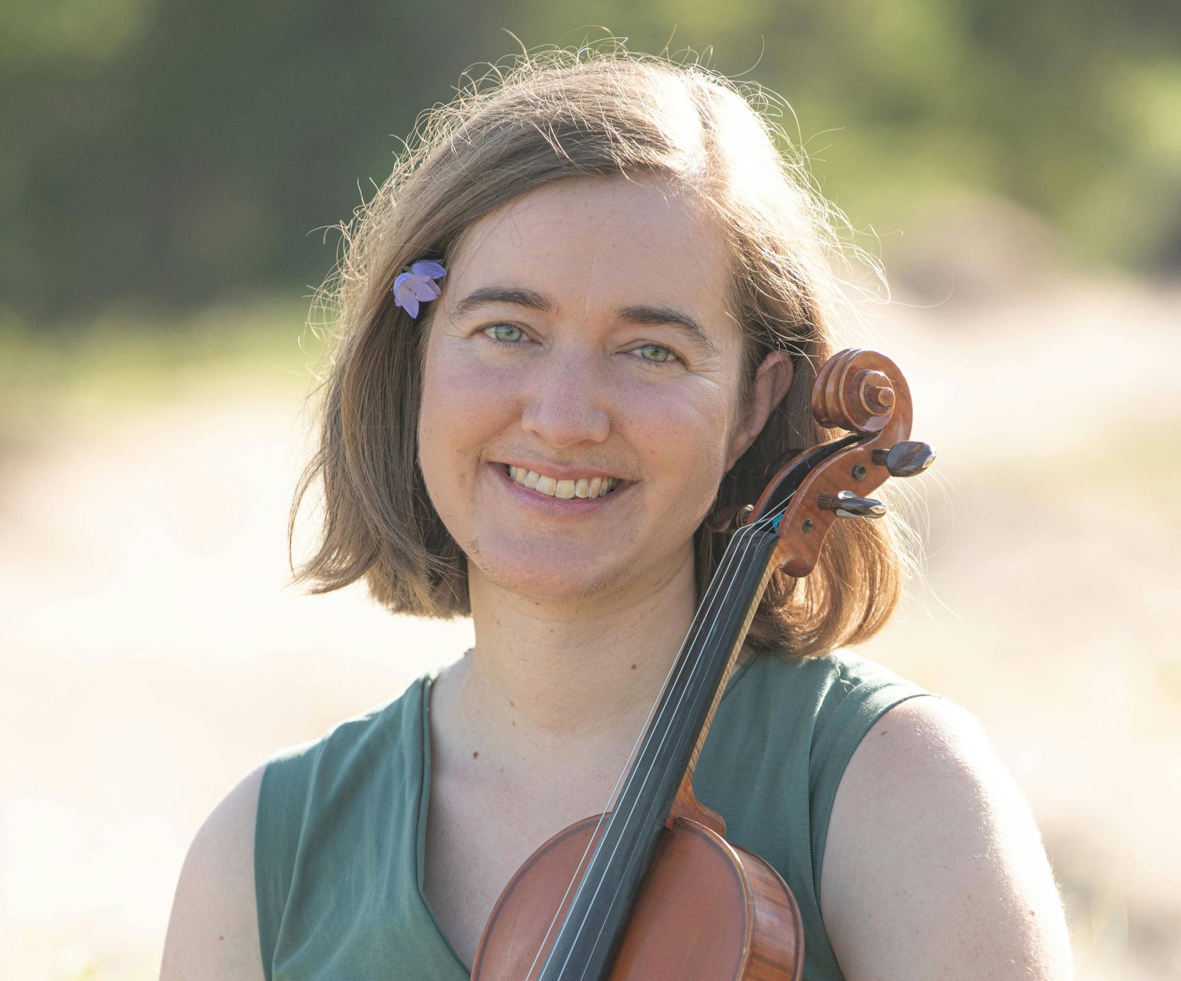 Hannah holds her fiddle in a sunflower field.