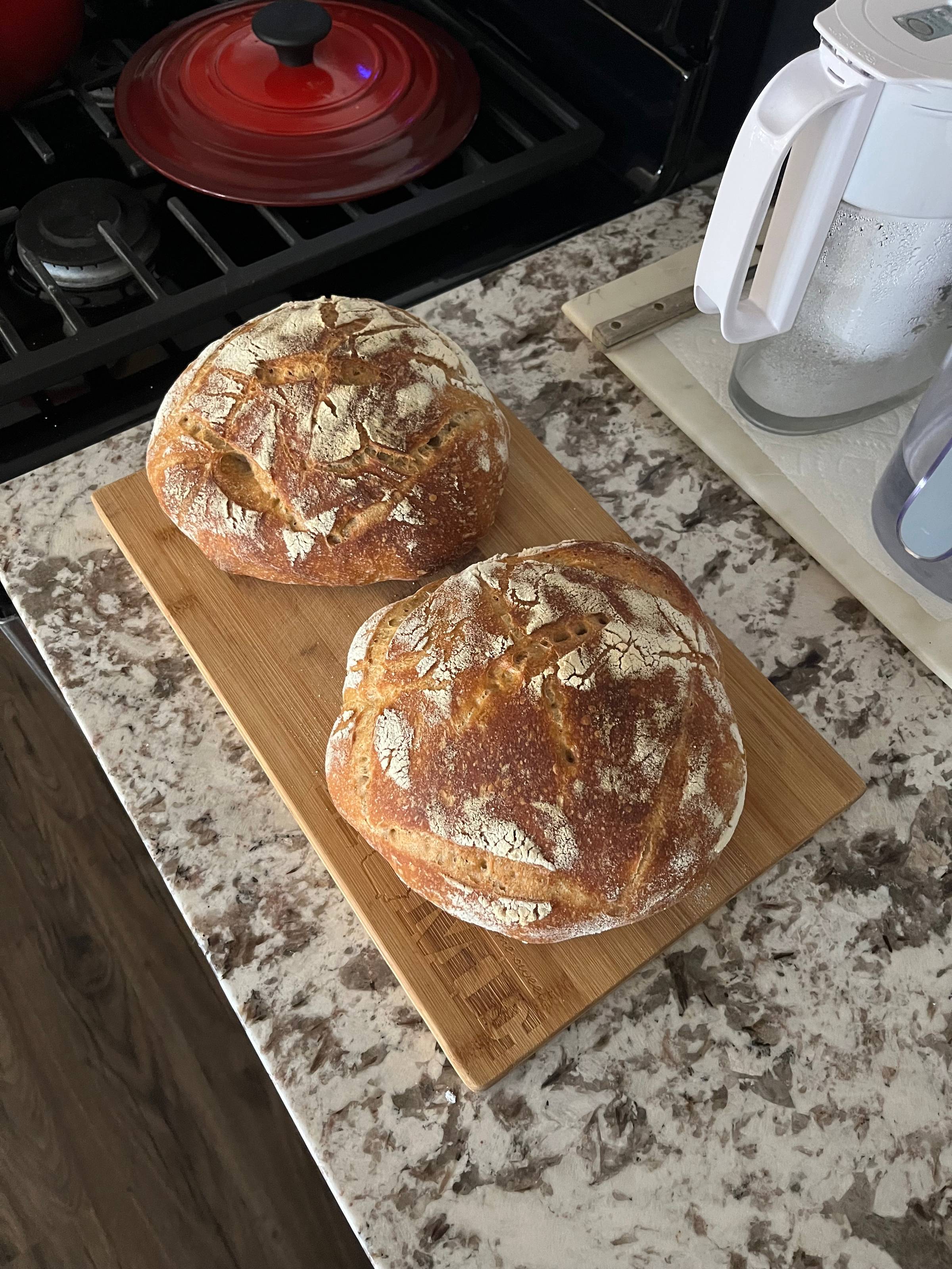 Two sourdough loaves on a white granite countertop