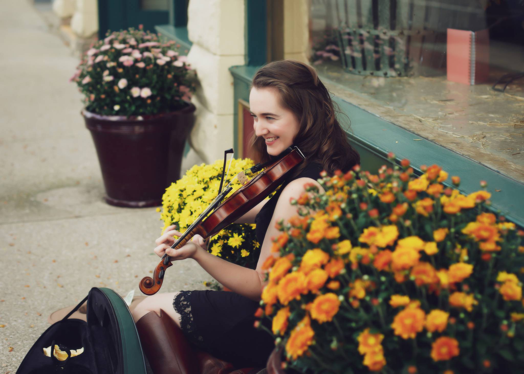 Hannah playing her fiddle behind a bouquet of mums