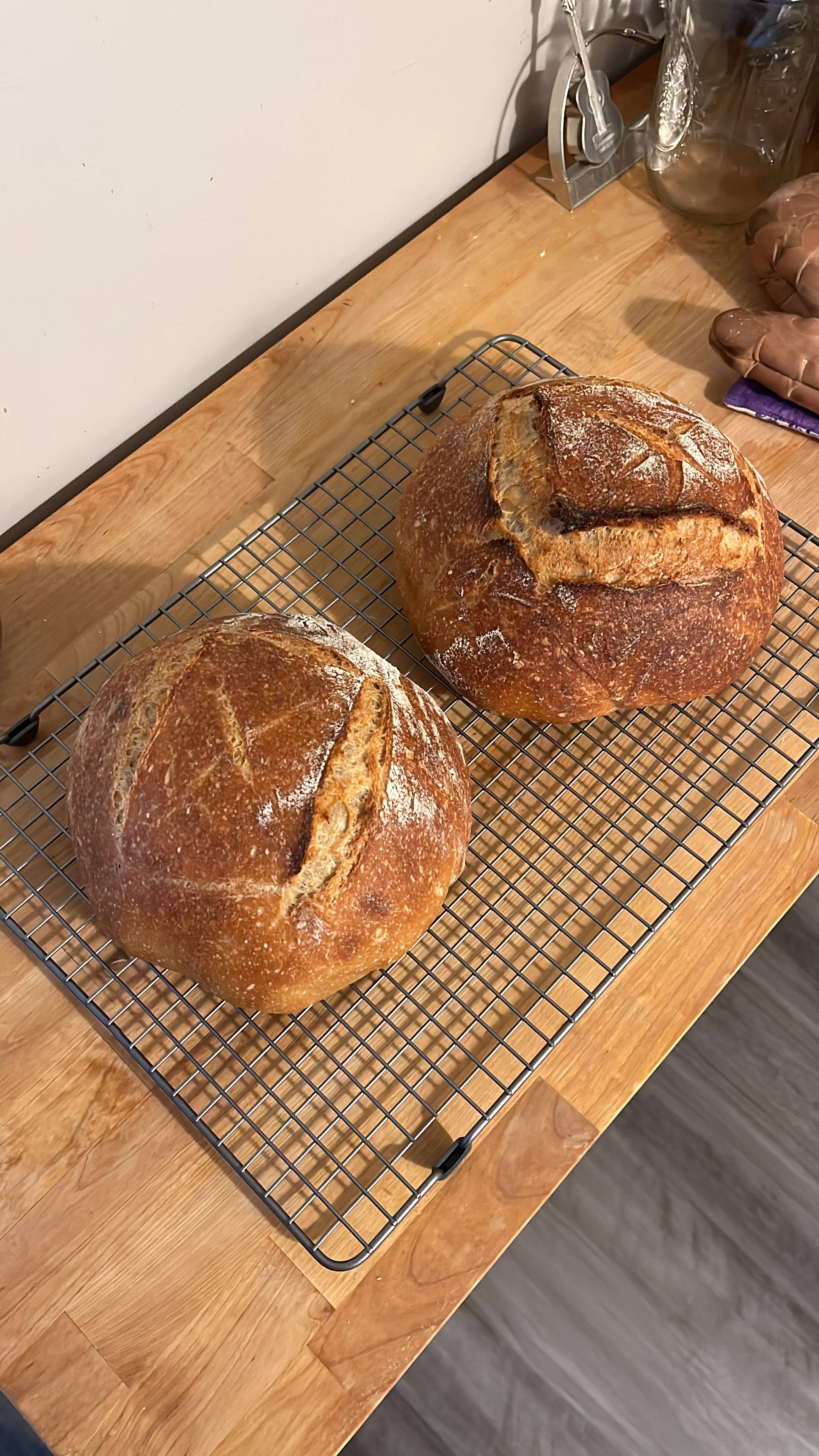 Two loaves of sourdough bread cooling on a wire rack