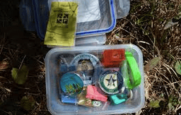 a plastic box full of misc items to take and give back for a geocache adventure