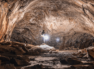 person walking with flashlight in a cave