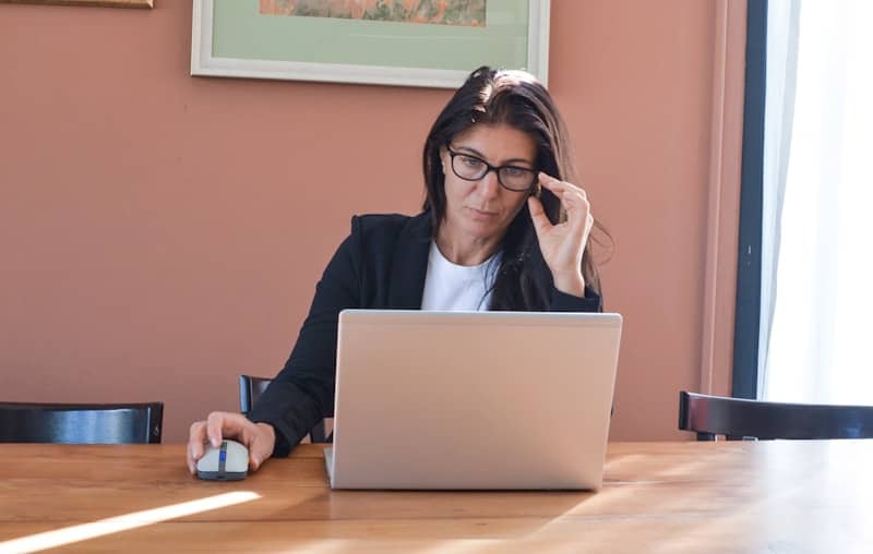 Woman in glasses working on laptop at desk