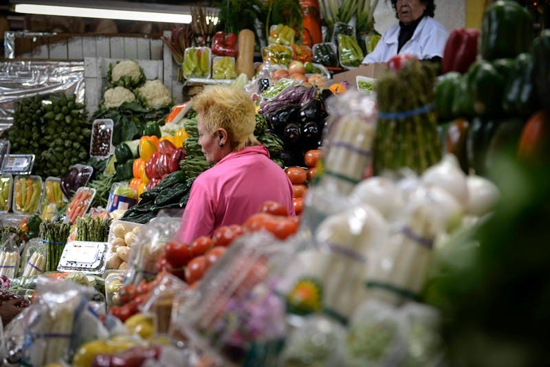 a woman standing in front of a display of fruits and vegetables