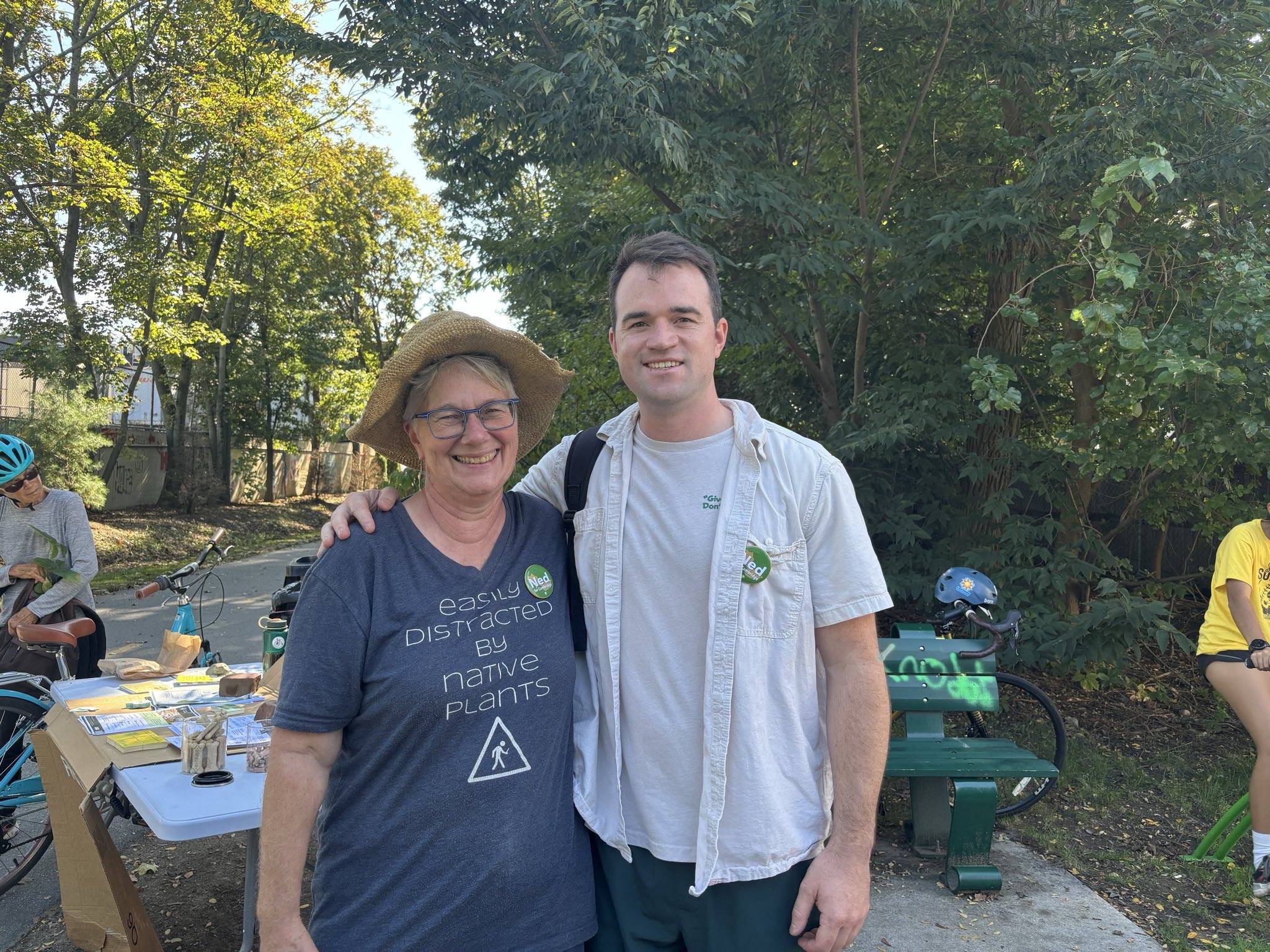 Ned posing with Cindy, who is wearing a Ned pin and a shirt that reads "Easily Distracted By Native Plants"