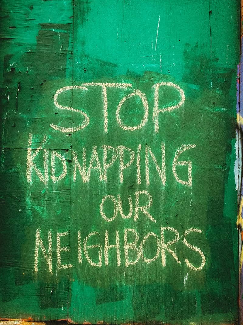 Stop kidnapping our neighbors message on green wall
