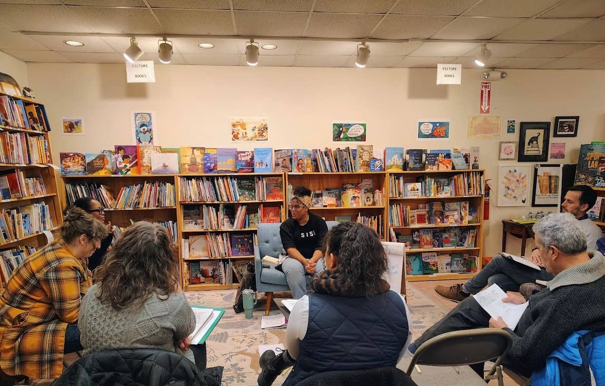 photo of writing workshop, with participants in a semi circle and Austin leading
