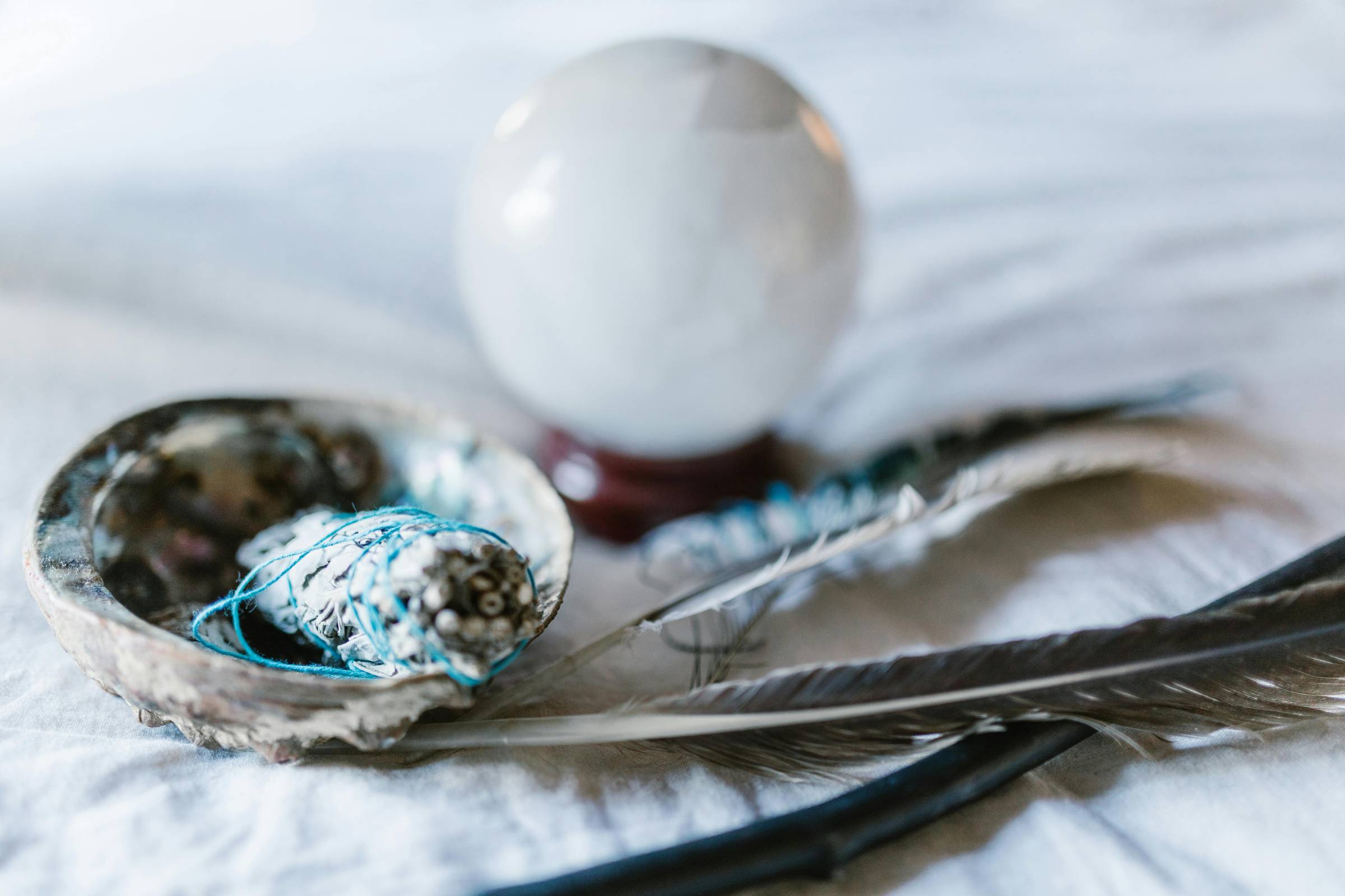 Sage stick for smudging, a crystal ball and feathers