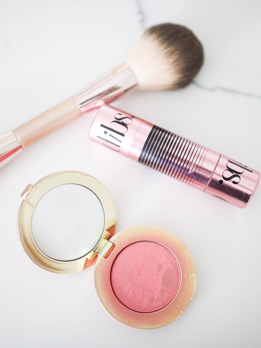 Dibs Beauty blush and bronzer duo with Too Faced pink blush and dual-ended makeup brush on a white background.