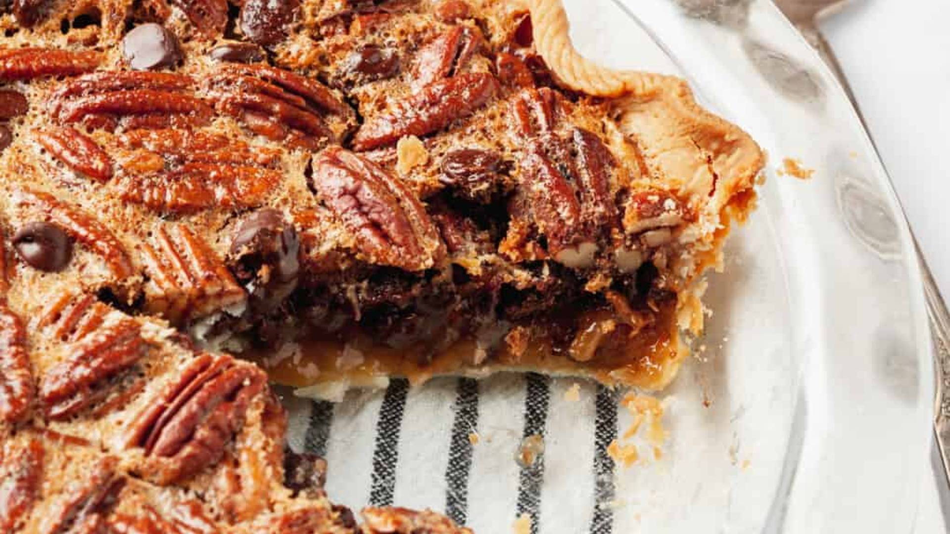 Homemade pecan pie with crackle top and a slice taken out.
