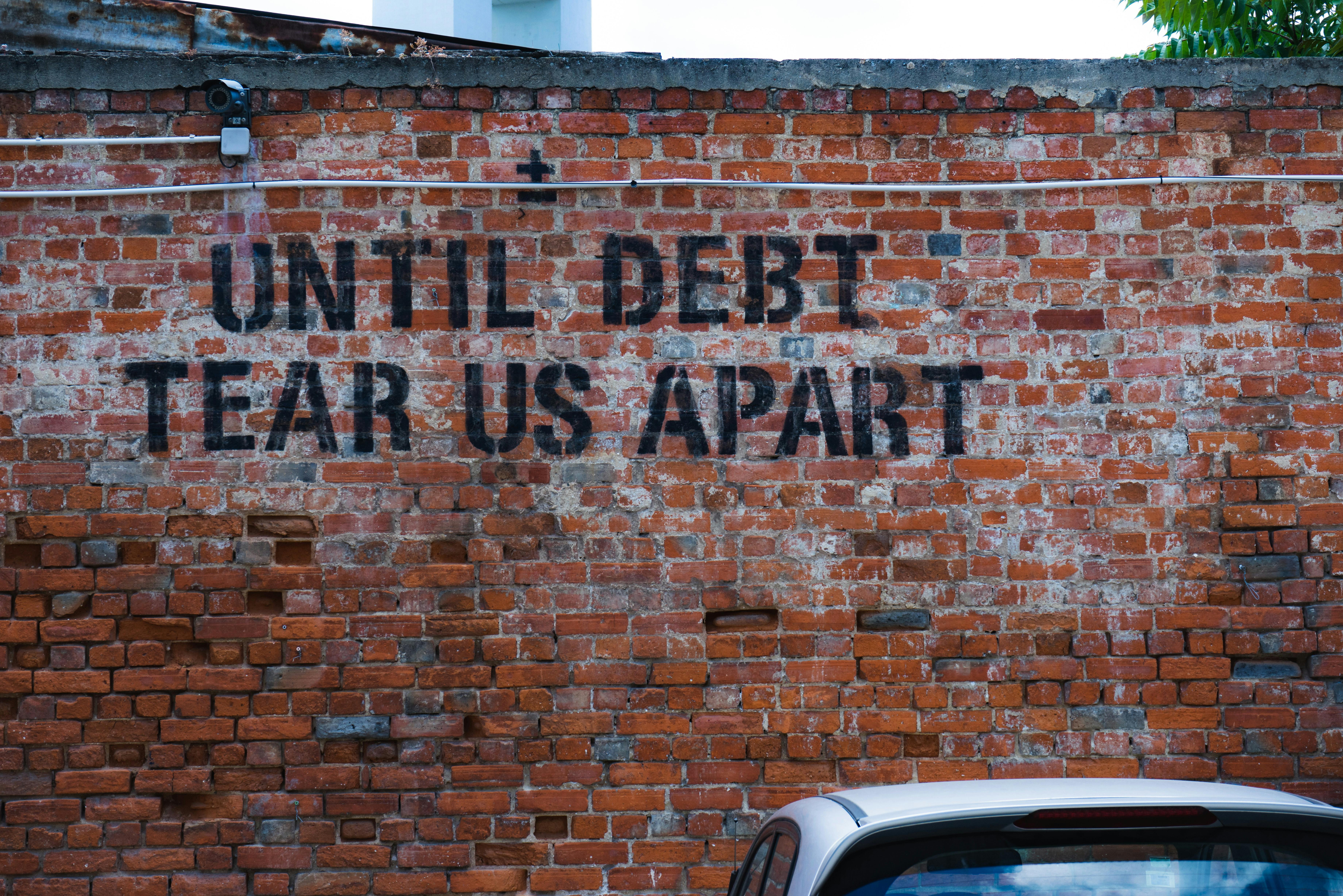 Graffiti on brick wall "UNTIL DEBT TEAR US APART"