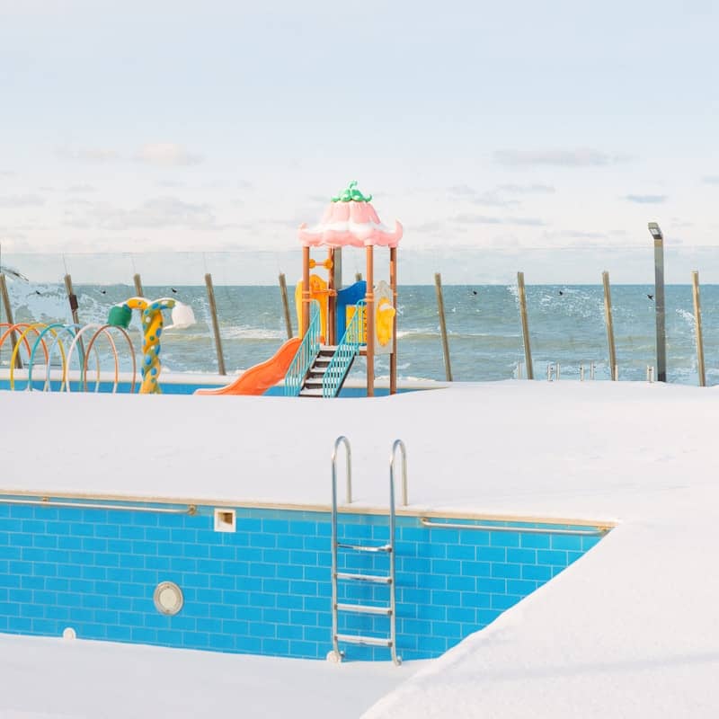 Empty swimming pool and playground covered in snow