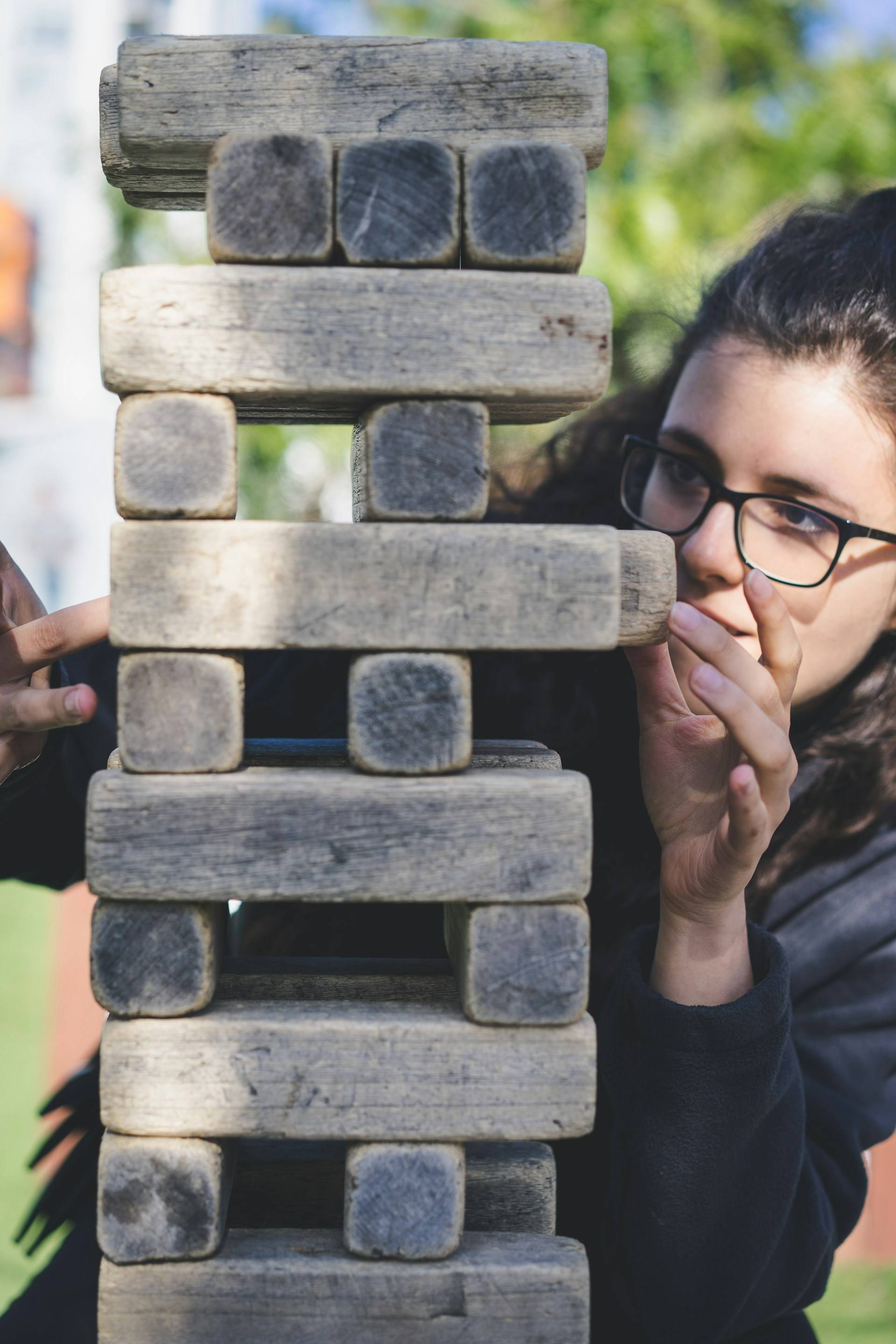 A woman adjusting large Jenga-style wooden blocks.
