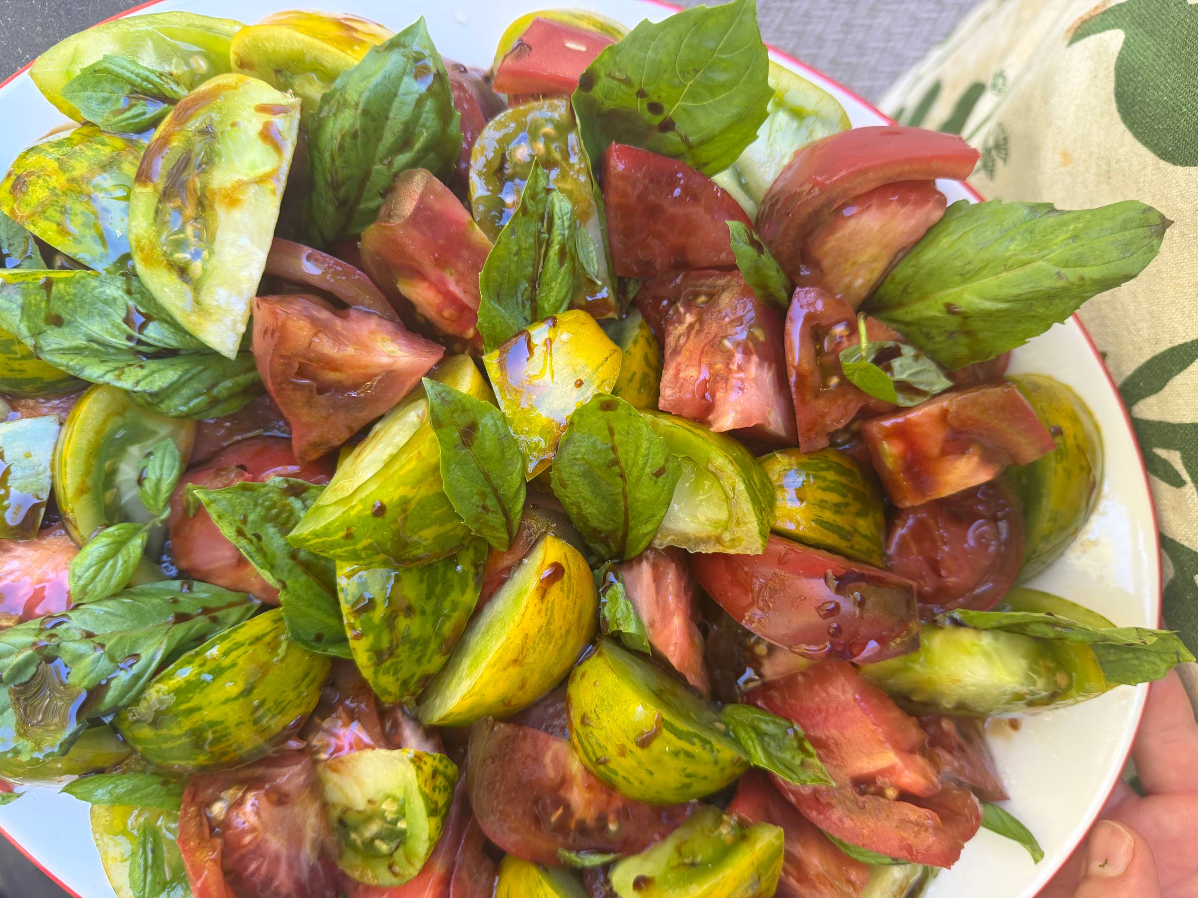 Heirloom tomatoes, basil, and olive oil and vinegar on a white platter.