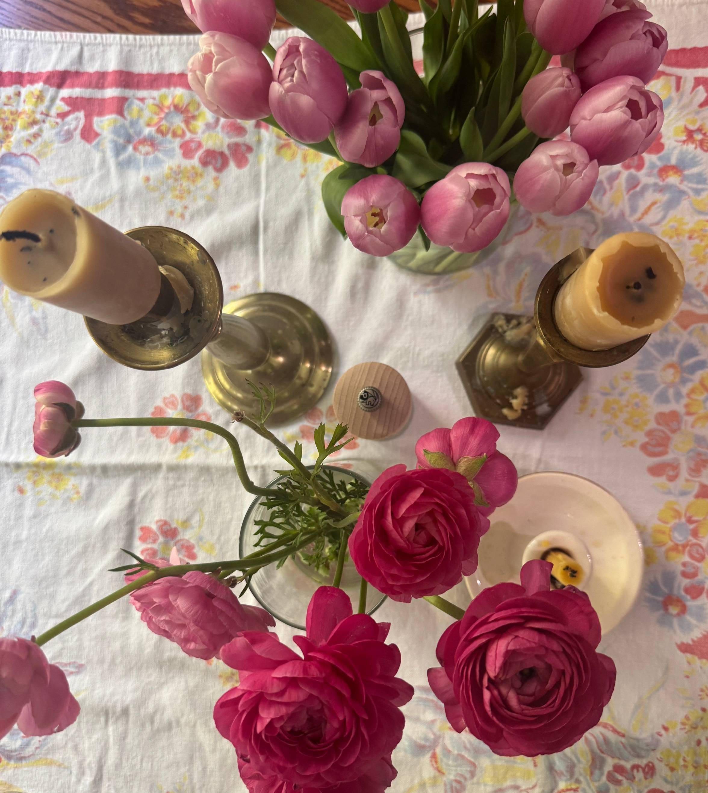 Tablescape for spring: flowers in vases, candles, and a vintage table cloth.