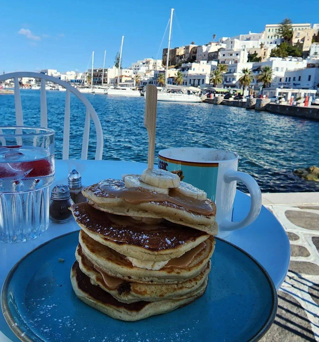 Pancakes on a plate next to Greek harbor
