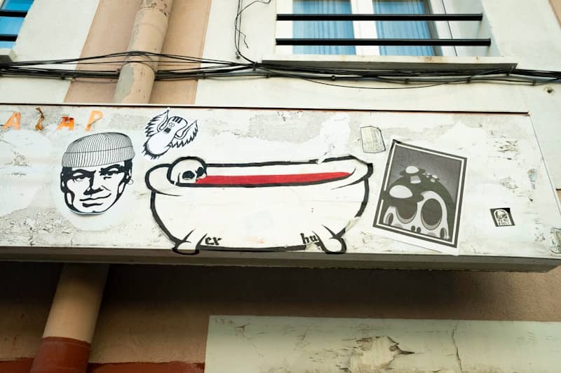 Graffiti art on a building exterior with bathtub illustration.