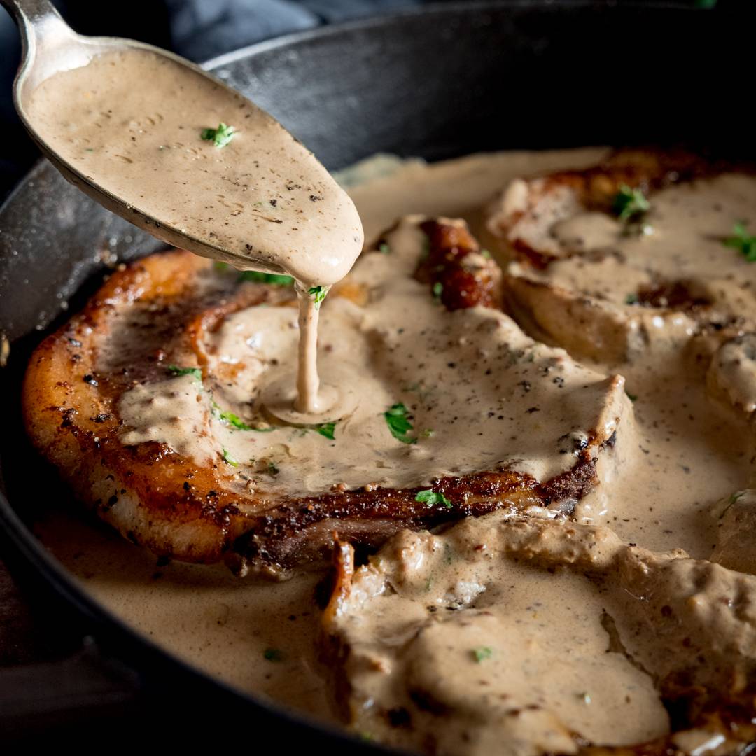 Pork Chops with creamy mustard sauce being poured over