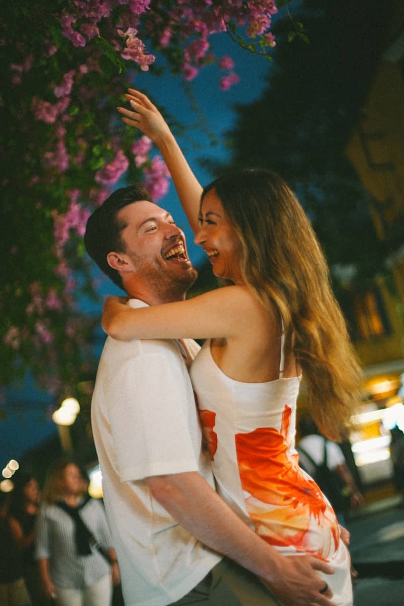 Couple laughing and embracing under blooming flowers