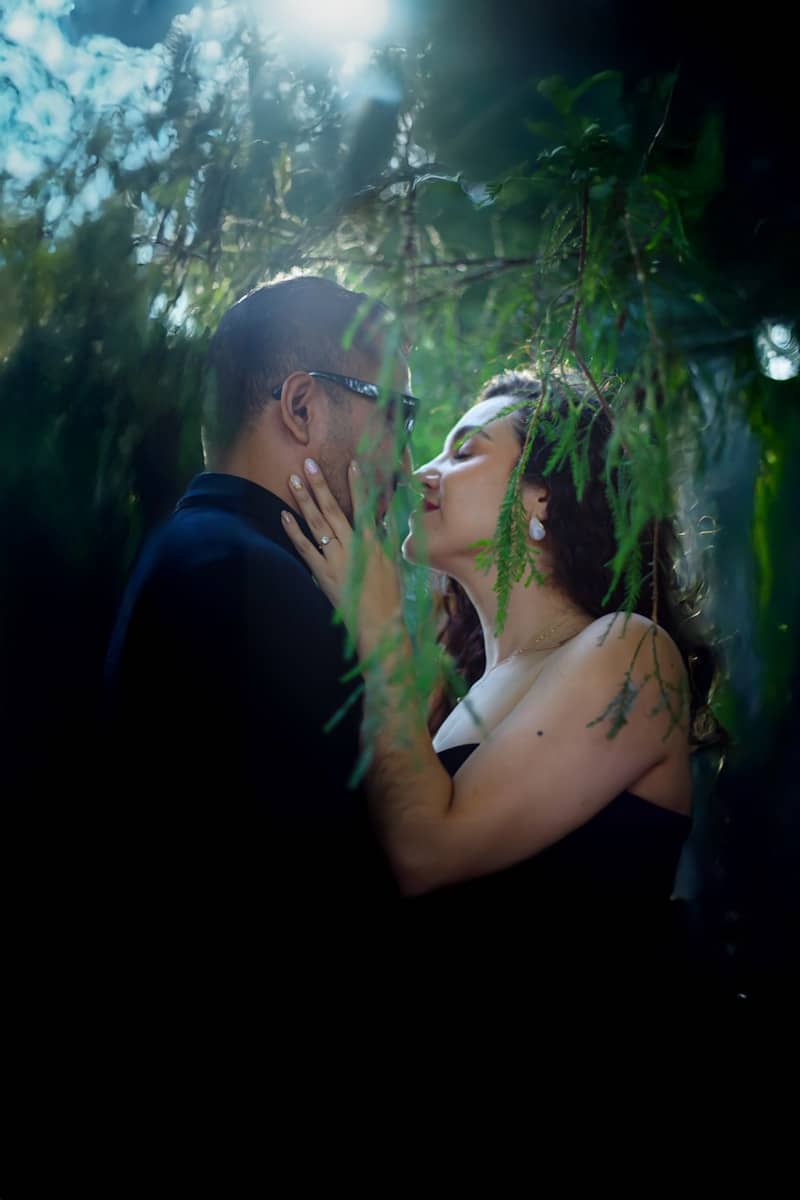 A man and a woman are kissing in the woods