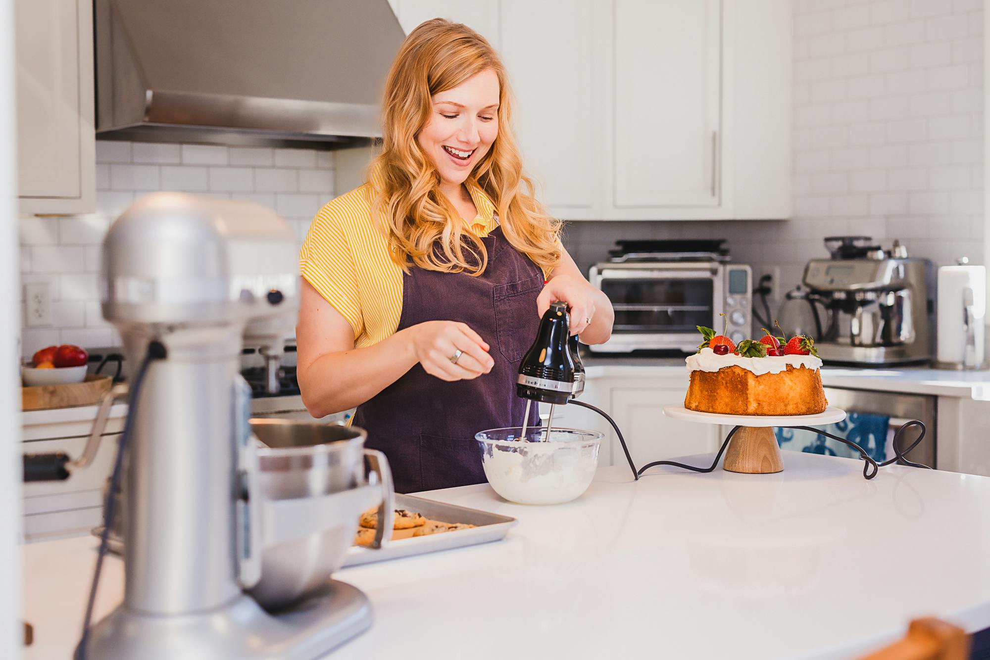 Leslie using a hand mixer at a kitchen island