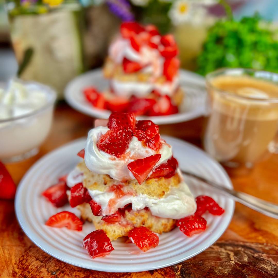 biscuit with whipped cream and strawberries on white plate