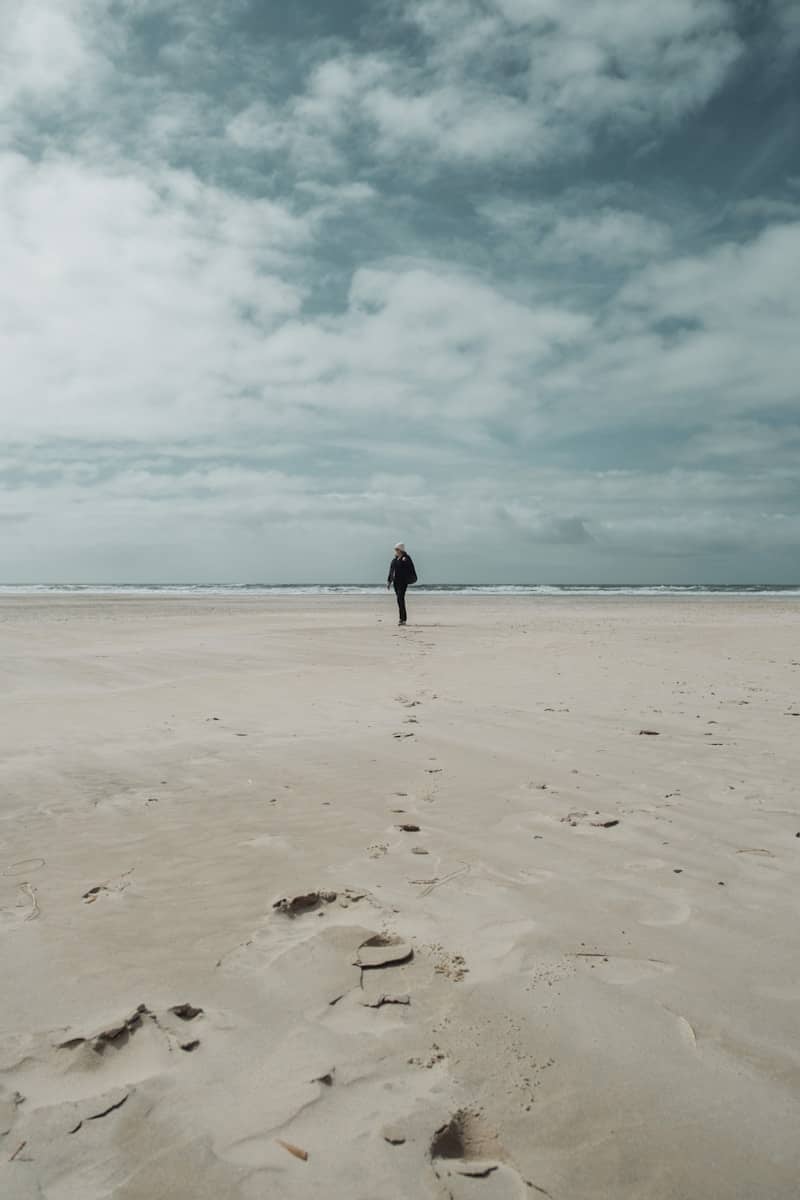 A person walks on the sandy beach.