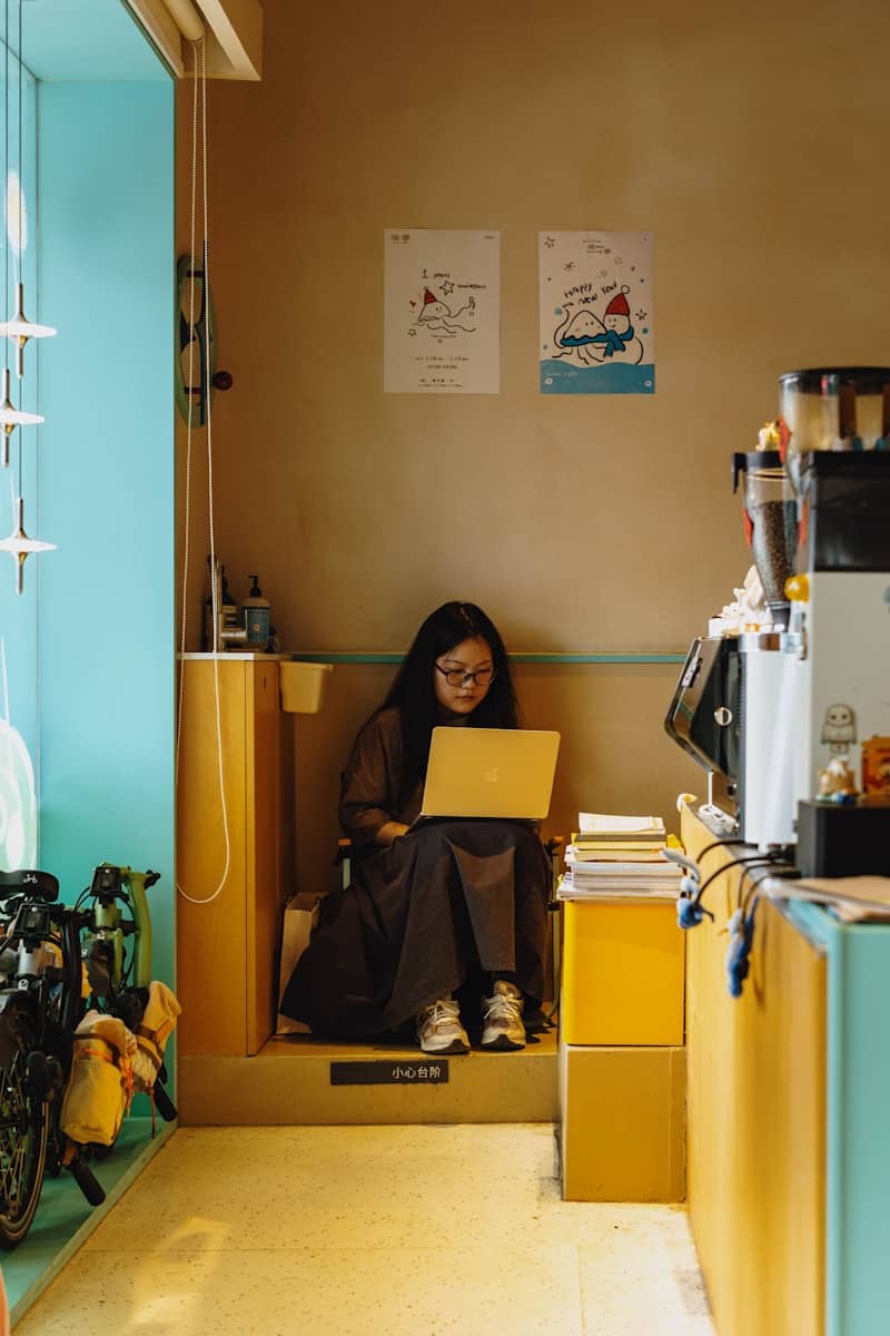 Woman focused on laptop in a vibrant cafe corner.