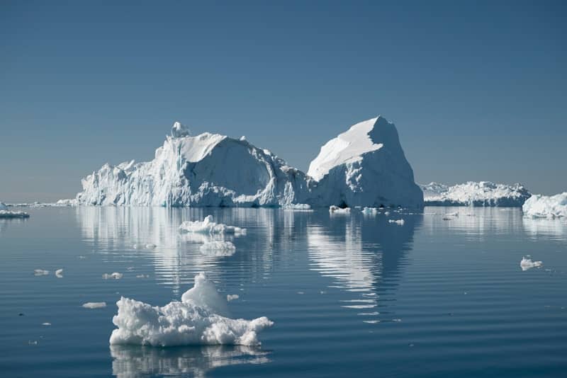 Large icebergs floating in a calm blue ocean.