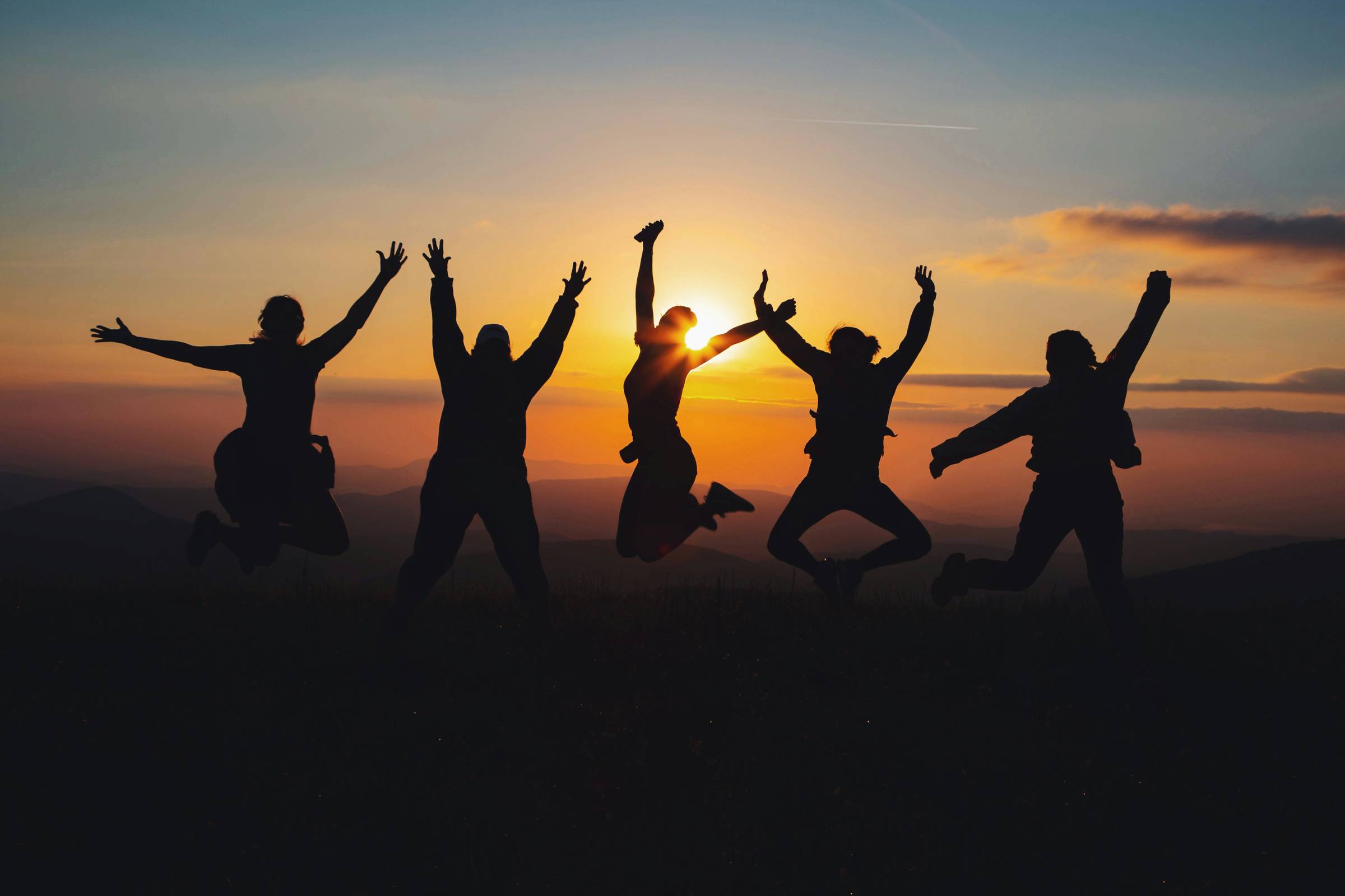 silhouette of people jumping at sunset