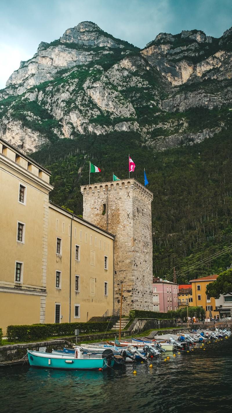 A castle and boats sit under a mountain.