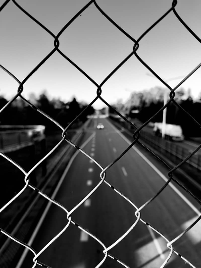 Chain-link fence in front of a highway.